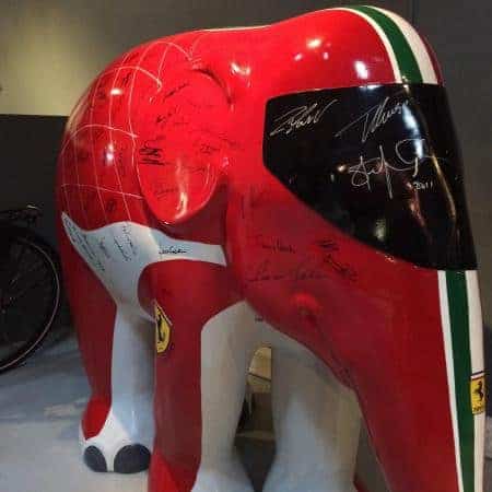 Éléphant Ferrari 1 Rzeźba czerwonego słonia z motywem i logotypem Ferrari na wystawie, ozdobiona podpisami.