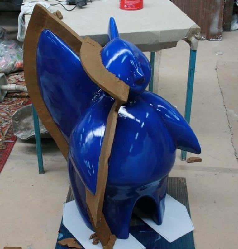 Niebieska figurka w foremce z brązowego kartonu, umieszczona na stole roboczym.