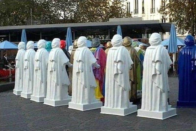 Réplique du monument Beethoven 4 Ludzie przebrani za posągi w białych i niebieskich szatach w parku miejskim.