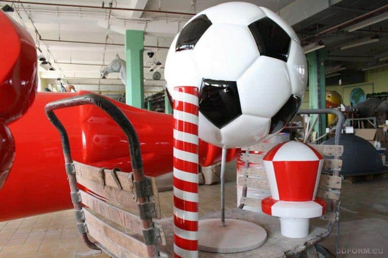 Bouteille Coca-Cola pour l'Euro 2012 1 Duże ozdobne elementy w kształcie piłki nożnej oraz czerwono-białego słupa wewnątrz warsztatu.