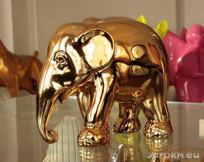 Figures métallisées, chromées 2 Figurka złotego słonia na szklanym stole.