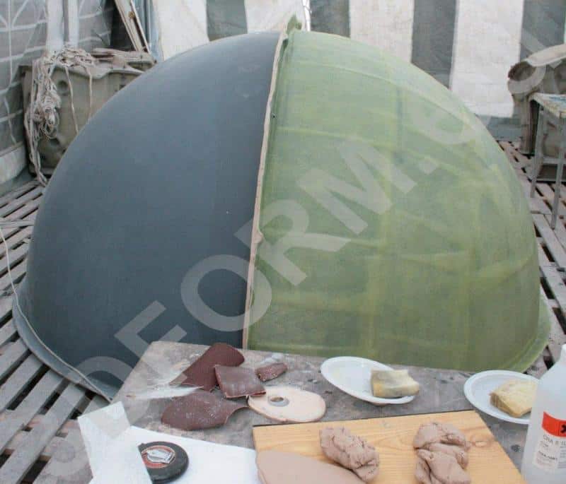 Grande Sphère dans l'Espace Urbain 3 Półokrągła konstrukcja w dwóch kolorach, otoczona narzędziami rzemieślniczymi na drewnianej podłodze.