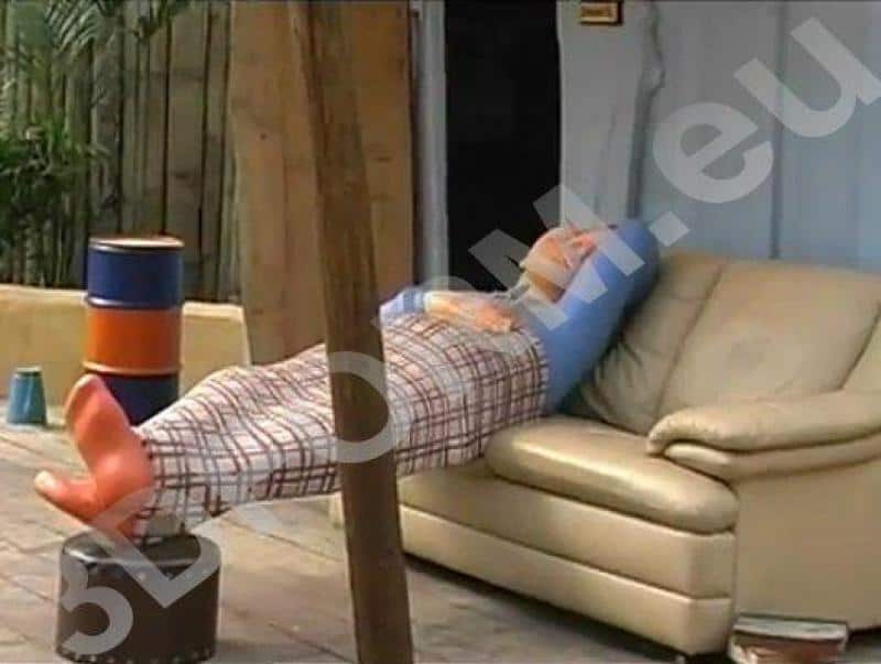 Figures pour parc d'attractions - Hugo Land 3 Mężczyzna leżący na kanapie na świeżym powietrzu, przykryty kocem, jego nogi podparte na beczce.