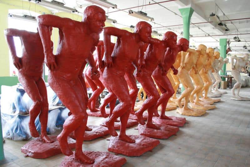 Promotion des Championnats du Monde IAAF 2 Figury męskich postaci w dziwnie wykręconej pozie, pomalowane na czerwono, pomarańczowo i biało, ustawione w rzędzie w przestrzeni magazynowej.