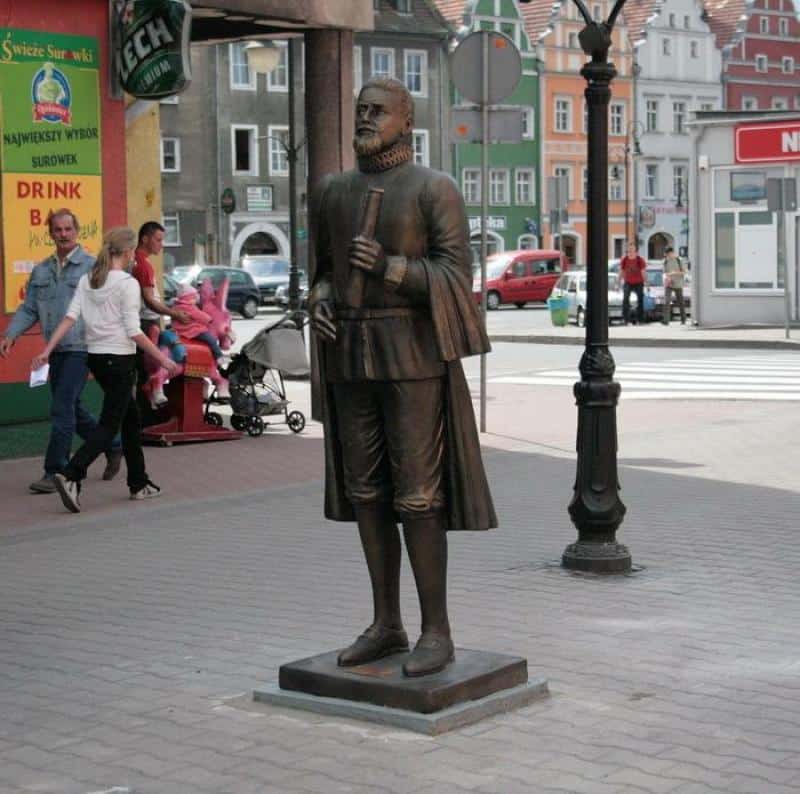 Monument - Kepler 1 Pomnik mężczyzny w historycznym stroju trzymającego zwój na ulicy w mieście.