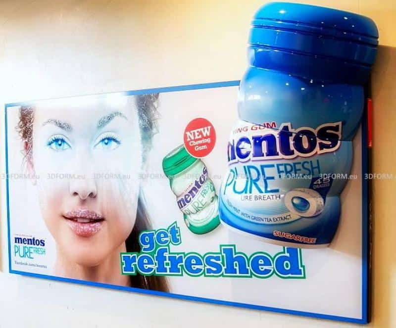 Reklama gum do żucia Mentos Pure Fresh z twarzą kobiety i dużym opakowaniem gumy w tle. Napis 