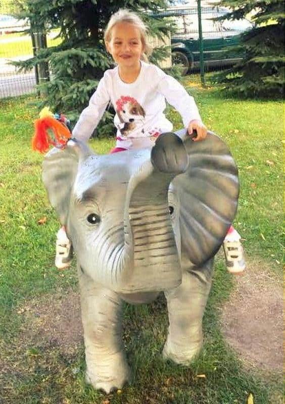 Figurines dans un parc à thème 5 Dziewczynka siedząca na figurce słonia na placu zabaw.