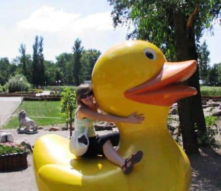 Figurines dans un parc à thème 3 Osoba obejmująca dużą plastikową żółtą kaczkę w parku.