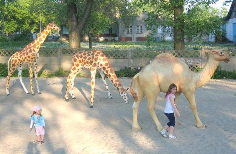Figurines dans un parc à thème 4 Dzieci bawiące się obok figur żyraf i wielbłąda w parku.