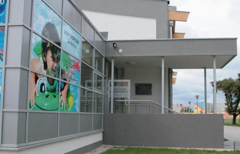 Panneau d'information décoratif 3 Budynek z dużym plakatem przedstawiającym dziecko na dmuchanym materacu oraz wejściem z napisem