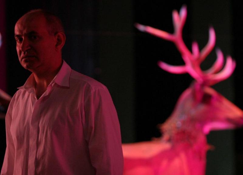 Éléments de scénographie pour le Théâtre Dramatique de la Ville Capitale de Varsovie 2 Mężczyzna w białej koszuli stojący obok różowo podświetlonego jelenia.