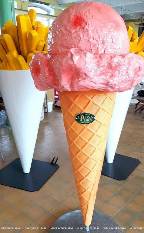 Maquette de glace - La Cabane Verte 3 Duży model lodów w rożku z różową gałką oraz duży model frytek w białym kubełku, w tle.