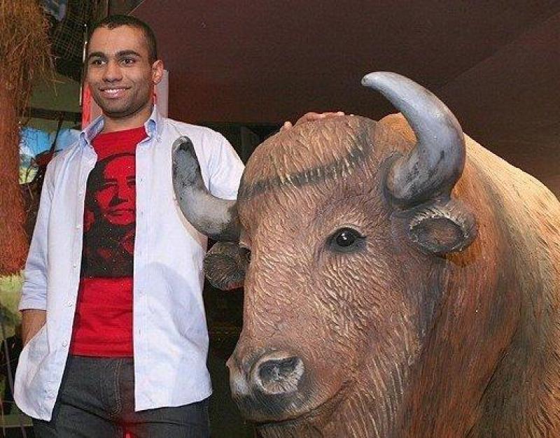 Bisons dans Mężczyzna stojący obok rzeźby żubra, trzymający rękę na jego grzbiecie.