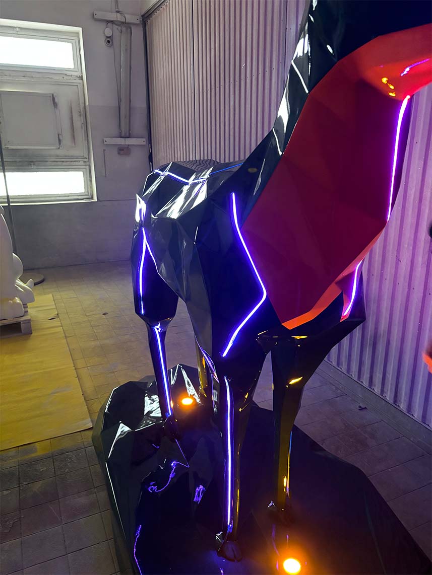 Rzeźba geometrycznego zwierzęcia z neonowymi światłami w warsztacie.