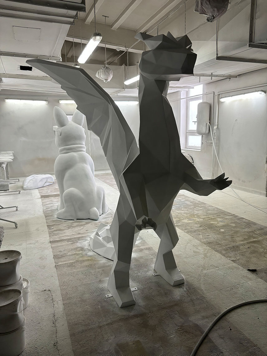 Abstrakcyjne rzeźby smoka i królika w pracowni artystycznej.