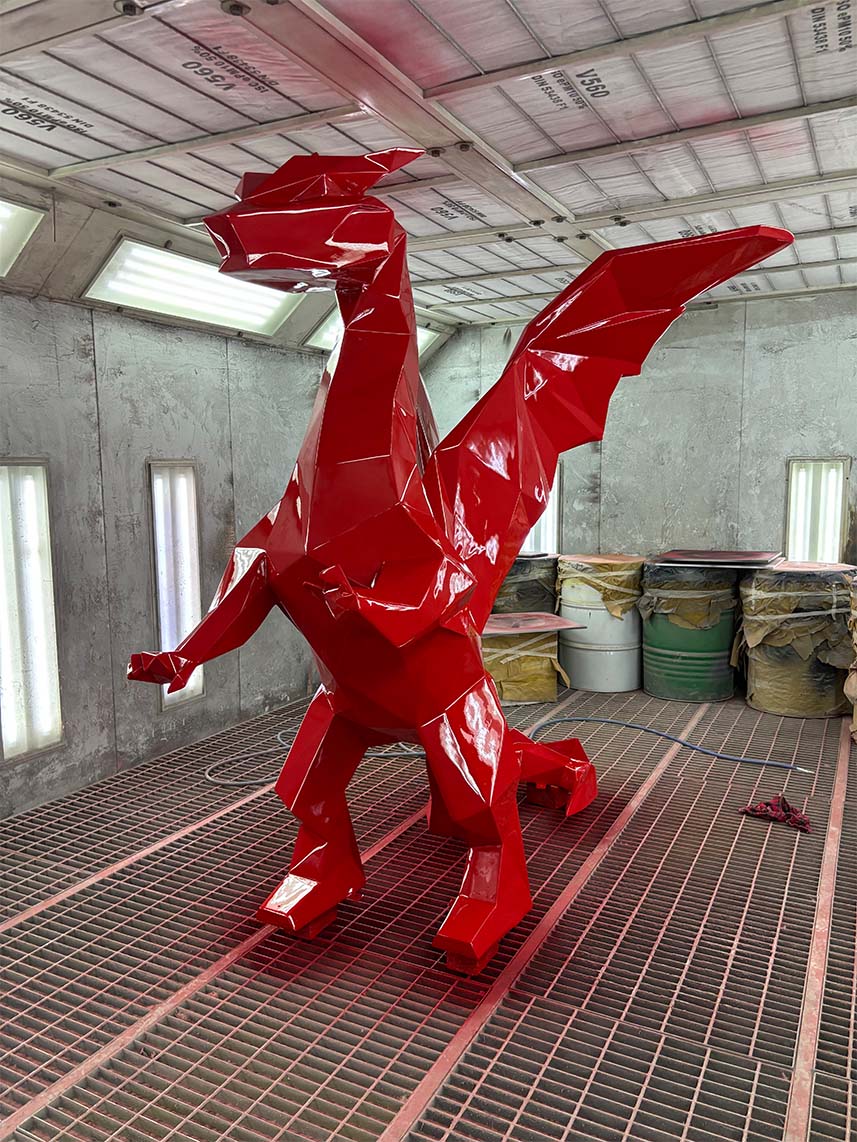 Czerwona, geometryczna rzeźba smoka w warsztacie malarskim.